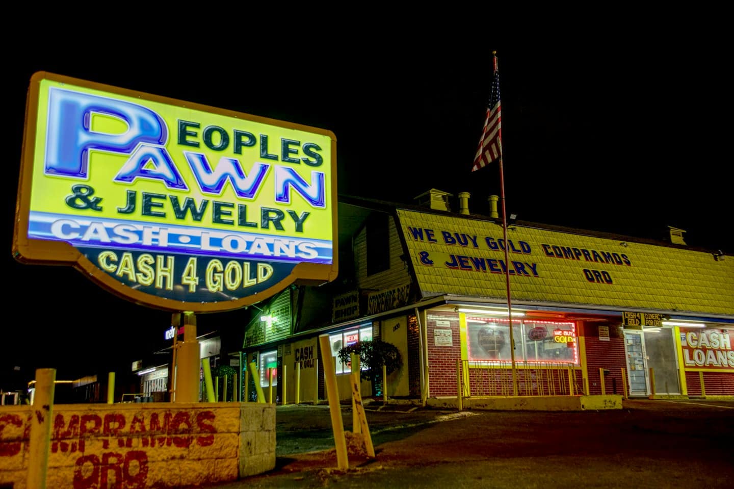 Jasno oświetlony nocą Peoples Pawn & Jewelry z neonowym szyldem.